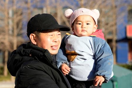北京市内の公園で祖父に抱かれた子ども＝２０２５年１２月（共同）