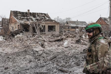 破壊された家の前を歩くウクライナ兵＝２０２５年１２月３１日、ウクライナ東部ドネツク州（ゲッティ＝共同）