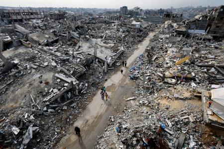破壊された住宅のがれきの中を歩くパレスチナ人＝２０２５年１２月３１日、ガザ北部ジャバリヤ（ロイター＝共同）