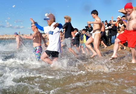 和歌山県田辺市の扇ケ浜海水浴場で開催された新春初泳ぎで、勢いよく海へ入る参加者たち＝２日午前