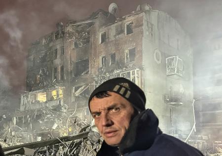 2日、ロシア軍の空爆で破壊されたアパートと男性住民=ウクライナ東部ハルキウ州(ロイター=共同)