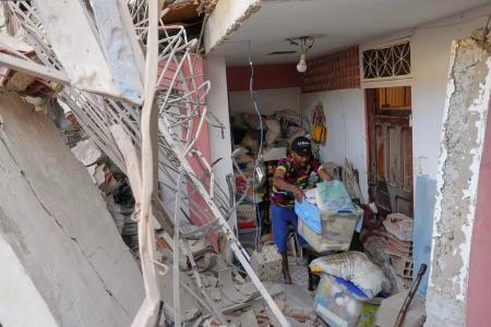 ４日、ベネズエラ首都カラカス近郊で、米国の攻撃で損壊したアパートを片付ける住民（ＡＰ＝共同）