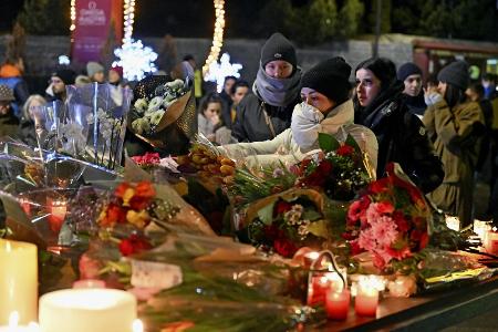 １日、スイス南部バレー州クランモンタナの火災現場周辺で、花やキャンドルなどを手向ける人たち（ゲッティ＝共同）