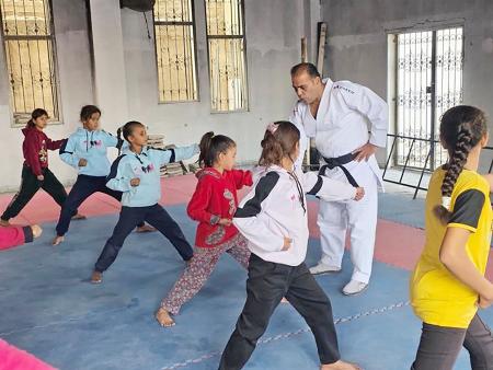 空手教室で練習する少女たち。奥で教えるのはハッサン・ライさん＝２０２５年１２月、ガザ市（共同）