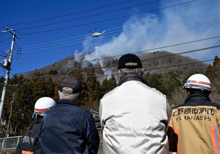 延焼が続く扇山で消火活動に当たるヘリコプター＝９日午前１０時２７分、山梨県上野原市