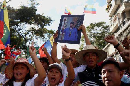 ８日、ベネズエラ・カラカスでマドゥロ大統領の写真を掲げ、解放を求める支持者ら（ロイター＝共同）