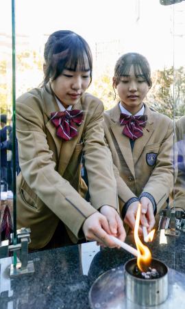 　「１・１７希望の灯り」の分灯が始まり、ろうそくに火を移す中学生＝１０日午後、神戸市中央区の東遊園地