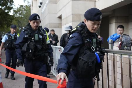 蘋果日報の創業者、黎智英氏の情状酌量を審理する公判前、裁判所周辺を警戒する警察官＝１２日、香港（共同）