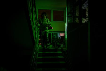 停電したウクライナ・キーウの住宅で懐中電灯をつける女性＝１３日（ＡＰ＝共同）