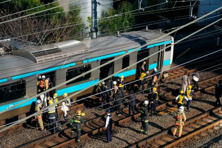 　高輪ゲートウェイ―田町間で停車したＪＲ京浜東北線の車両から線路に降りる乗客＝１６日午前９時７分、東京都港区