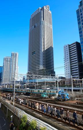 新橋―浜松町間で停車したＪＲ京浜東北線の車両から降りて線路を歩く乗客＝１６日午前１０時４分、東京都港区