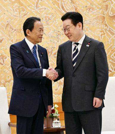 韓国の李在明大統領（右）と握手を交わす自民党の麻生副総裁＝１６日、韓国大統領府（共同）