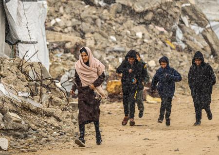 １８日、ガザ北部ガザ市で、がれきの中を歩くパレスチナ人（ゲッティ＝共同）