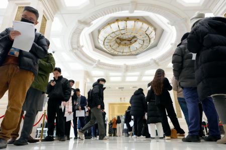 中国国家統計局のＧＤＰ速報値に関する資料を受け取るために並ぶ報道関係者ら＝１９日、北京（共同）