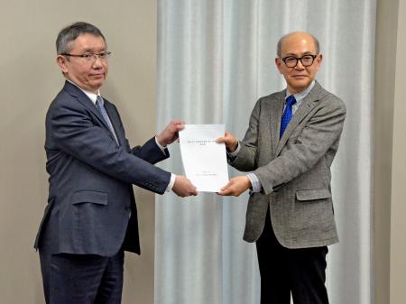 気象庁の野村竜一長官（左）に報告書を手渡す京都大防災研究所の矢守克也教授＝２０日午後、気象庁