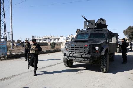 ２０日、シリア北東部ハサカ県で、装甲車両のそばを歩くシリア民主軍（ＳＤＦ）の戦闘員ら（ロイター＝共同）