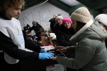 ２０日、キーウで、停電中にテント内で食事を配る男性（ロイター＝共同）