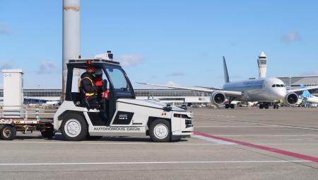 誘導路手前で自動停止し、航空機の通過を待つ自動運転の貨物けん引車＝２２日午前、中部空港