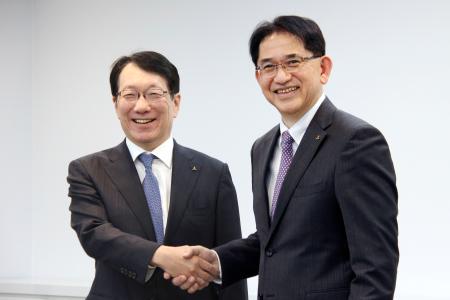 三菱自動車の加藤隆雄社長（左）と握手する、次期社長就任が決まった岸浦恵介氏＝２２日午後、東京都港区