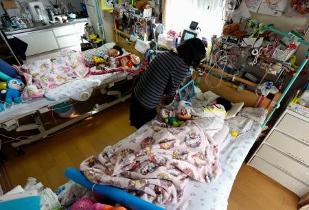 自宅で医療的ケアが必要な小学生の双子を育てるシングルマザー（中央）＝２５日、名古屋市