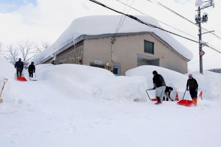 建物の周囲を除雪する人たち＝２日午後、青森市