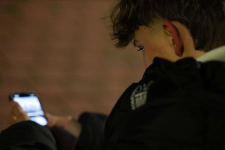 ３日、スペイン・マドリード郊外で、スマートフォンの画面をスクロールする１４歳の子ども（ロイター＝共同）