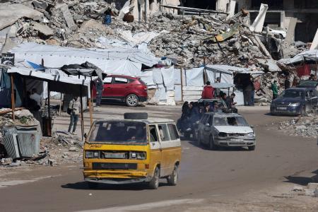 　イスラエルの攻撃で破壊された住宅のがれきの間を通るパレスチナの人々の車＝４日、ガザ市（ロイター＝共同）