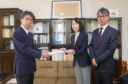 文科省の望月禎初等中等教育局長（左）に、意見書を手渡す日本新聞協会の坂口佳代ＮＩＥ委員会委員長（中央）＝６日、東京都千代田区（日本新聞協会提供）