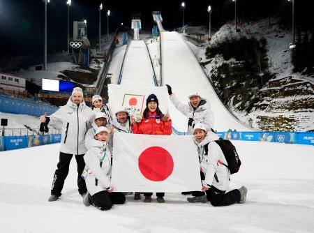 　女子個人ノーマルヒルで銅メダルを獲得し、チームスタッフらと喜ぶ丸山希（右から３人目）＝プレダッツォ（共同）