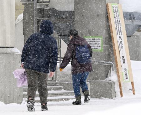　雪が降る中、札幌市内の投票所に向かう人たち＝８日午後