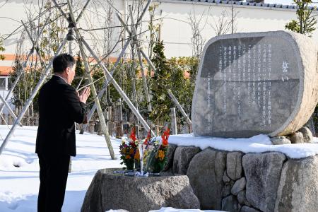 慰霊碑に手を合わせる三幸製菓の牛腸栄一社長＝１０日午前、新潟県村上市