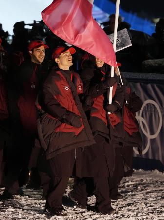 ミラノ・コルティナ冬季五輪の開会式で、旗手を務めるカナダのミカエル・キングズベリー(中央)=6日、イタリア・リビーニョ