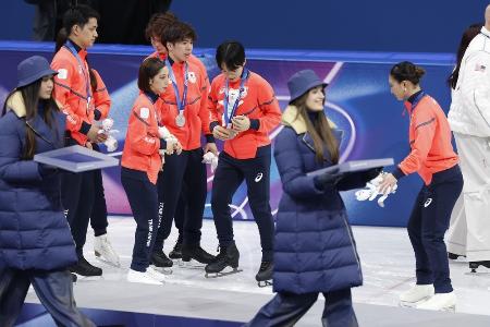 表彰台（手前）から下りた後、靴のブレードの状態を確認する（奥右から）坂本花織、鍵山優真ら＝８日、ミラノ
