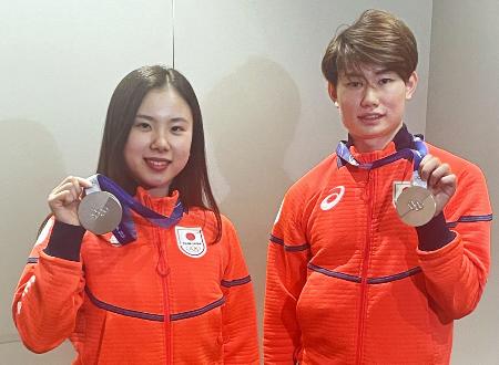 帰国し、フィギュアスケート団体で獲得した銀メダルを掲げるアイスダンスの吉田唄菜（左）と森田真沙也＝１１日、羽田空港