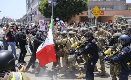 ２０２５年６月、米ロサンゼルスの連邦施設付近で衝突する州兵と移民摘発の抗議者ら（共同）