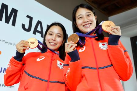 記者会見でメダルを掲げるノルディックスキー・ジャンプ女子の高梨沙羅（左）と丸山希＝１６日、イタリア・ミラノ（共同）