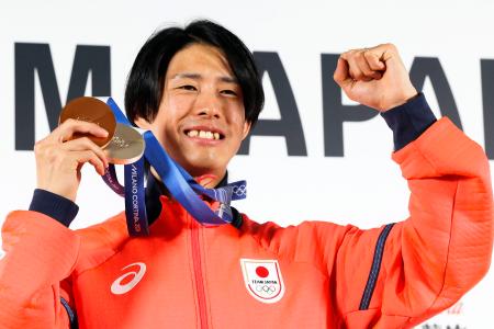 記者会見を終え、メダルを手にポーズをとる、フリースタイルスキーの堀島行真=17日、イタリア・ミラノ(共同)