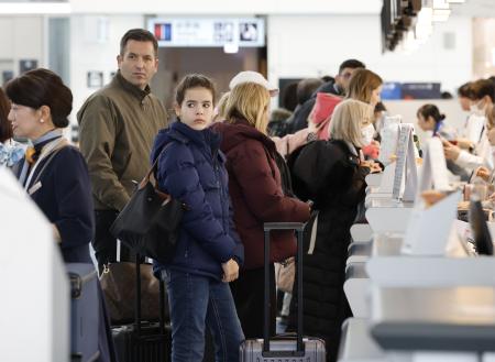 羽田空港の国際線出発ロビーで手続きをする訪日客ら＝１８日午前