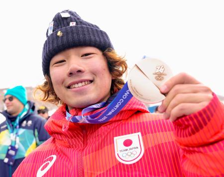 ミラノ・コルティナ冬季五輪のスノーボード男子スロープスタイルで銀メダルを獲得し、笑顔を見せる長谷川帝勝=18日、イタリア・リビーニョ(共同)