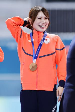女子団体追い抜きで銅メダルを獲得し、表彰台で笑顔の佐藤綾乃＝１７日、ミラノ（共同）