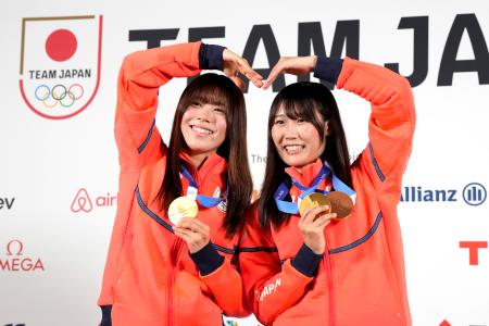 記者会見でメダルを掲げるスノーボード女子の深田茉莉（左）と村瀬心椛＝２０日、イタリア・ミラノ（共同）