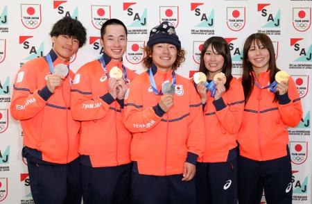 帰国後の記者会見でメダルを掲げるスノーボードの（左から）木俣椋真、木村葵来、長谷川帝勝、村瀬心椛、深田茉莉＝２２日午後、成田空港