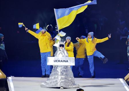 ミラノ・コルティナ冬季五輪の開会式で、プラカードを持ってウクライナ選手団を先導するロシア人のクチェロワさん=6日、イタリア・ミラノ(共同)