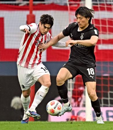 競り合うフライブルクの鈴木唯（左）とボルシアＭＧの町野＝フライブルク（共同）