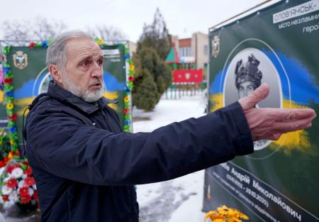 息子の遺影の前で取材に応じるミコラ・シロババさん＝２３日、スラビャンスク（共同）