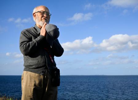 米軍に撃沈された艦艇が沈む沖合に向かって手を合わせる遺族の吉田進さん＝１日午後、沖縄県宮古島市