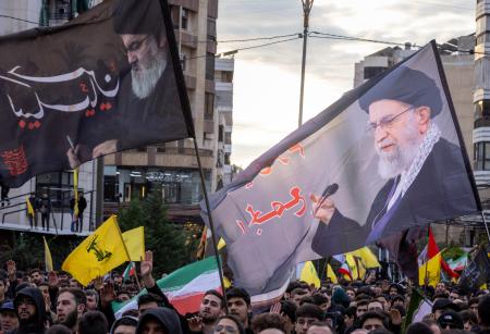 １日、レバノンの首都ベイルートでの集会で、イラン最高指導者ハメネイ師の旗（右）と、レバノンの親イラン民兵組織ヒズボラの指導者だった故ナスララ師の旗を掲げる人たち（ゲッティ＝共同）
