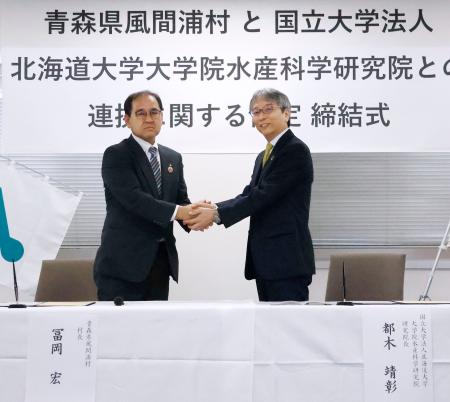 協定締結式で握手する、青森県風間浦村の冨岡宏村長（左）と北海道大大学院水産科学研究院の都木靖彰研究院長＝３日午前、北海道函館市