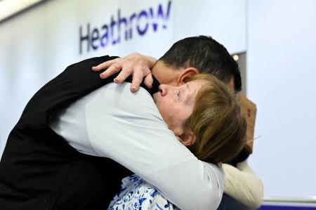 ６日、英ロンドンのヒースロー空港で、オマーンから到着後に抱擁される乗客（ロイター＝共同）