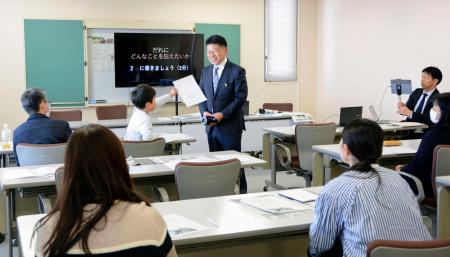 東日本大震災にちなんだ広告企画を教材に模擬授業をする光武正夫さん（中央）＝７日午後、佐賀市